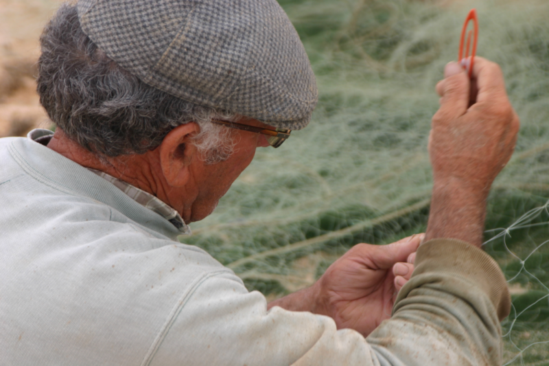 Pescador local a remendar a rede